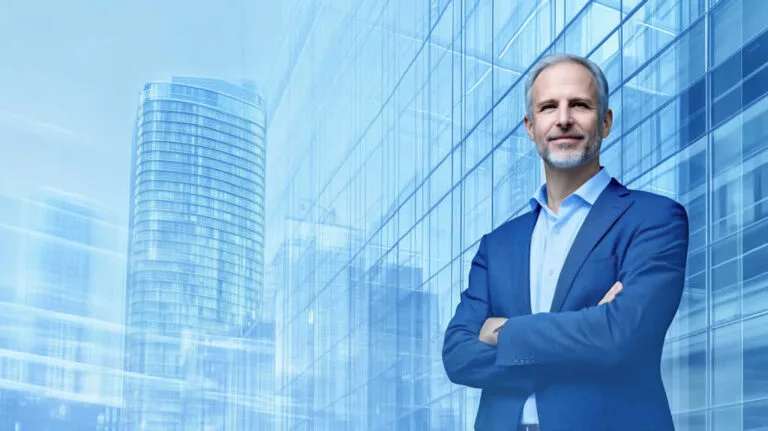 Confident businessman standing in front of modern skyscraper.