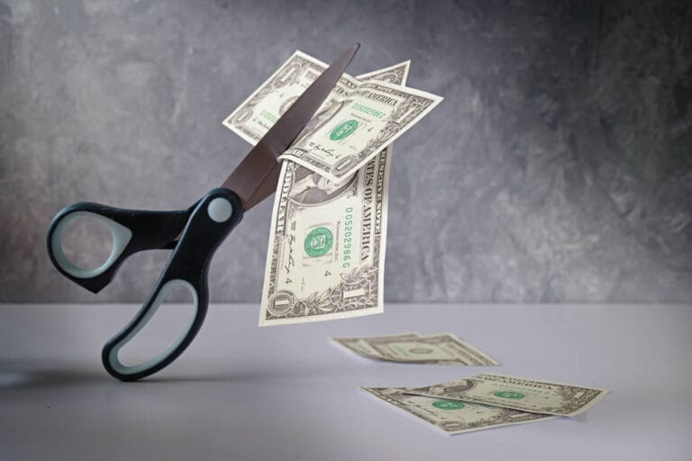 Scissors cutting through dollar bills