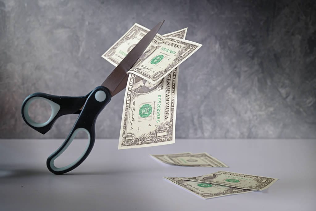 Scissors cutting through dollar bills