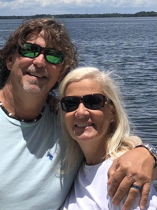Couple smiling by a lake with sunglasses.