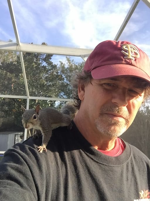 Man with squirrel on shoulder outdoors
