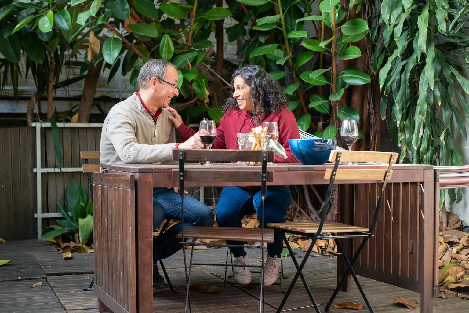 Happy senior couple having a fun picnic with drinks in a lush garden setting.