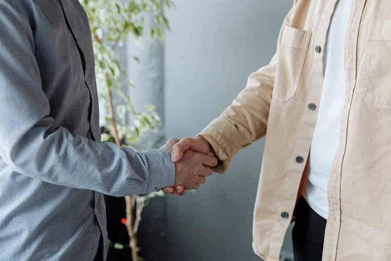 A close-up image of two businesspeople shaking hands in an office environment symbolizing agreement and partnership.