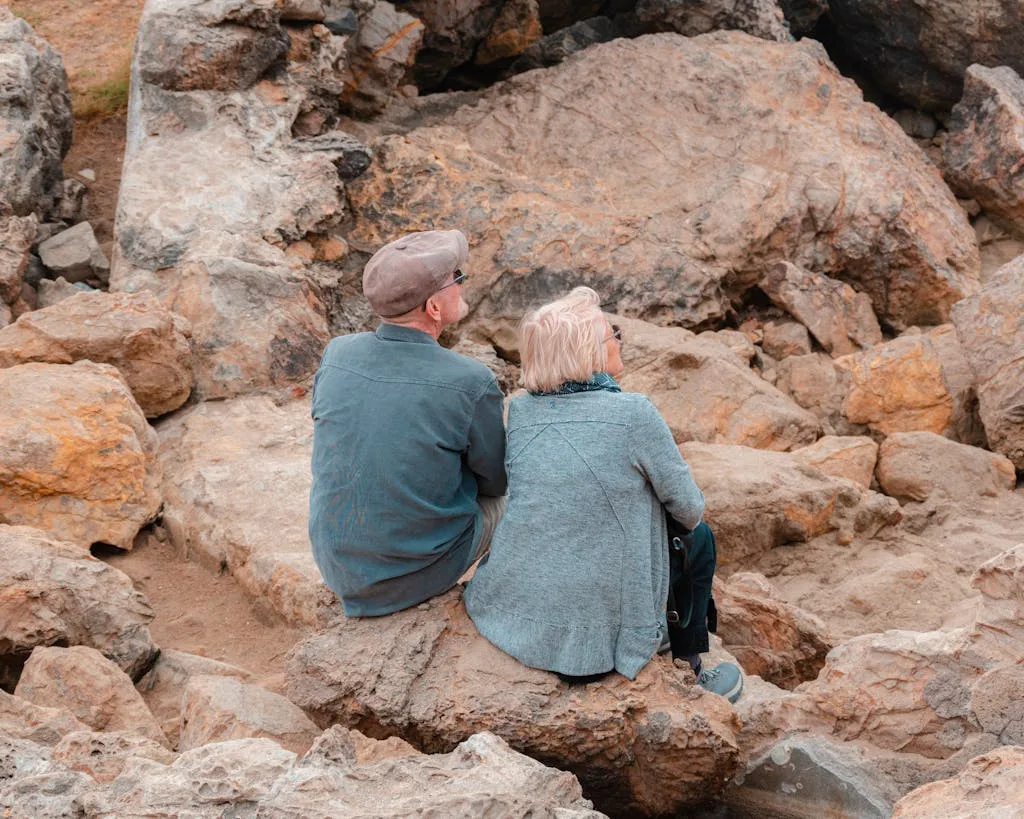 Elderly couple sitting on rocky terrain in San Francisco, enjoying outdoor scenery.
