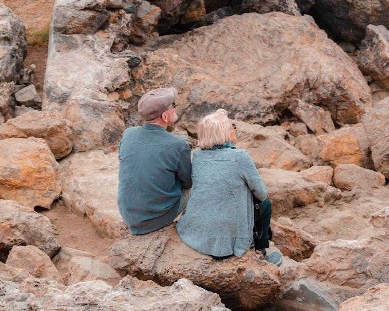 Elderly couple sitting on rocky terrain in San Francisco, enjoying outdoor scenery.