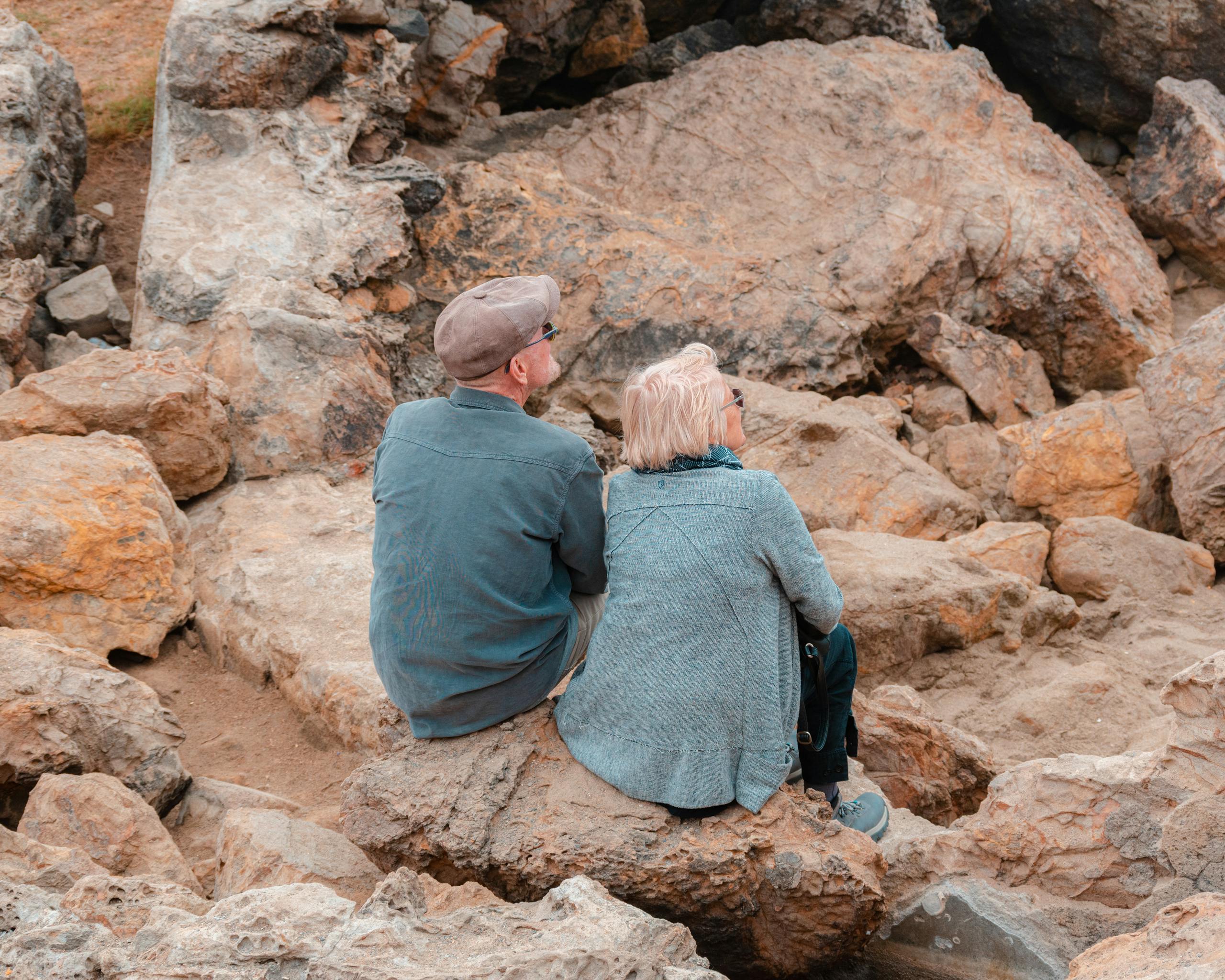 Elderly couple sitting on rocky terrain in San Francisco, enjoying outdoor scenery.