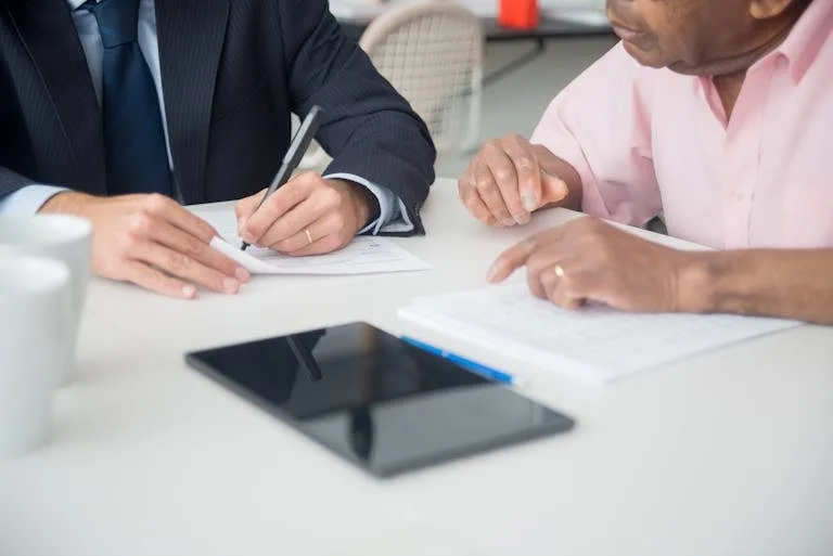 Two professionals discussing and signing documents in a business meeting.